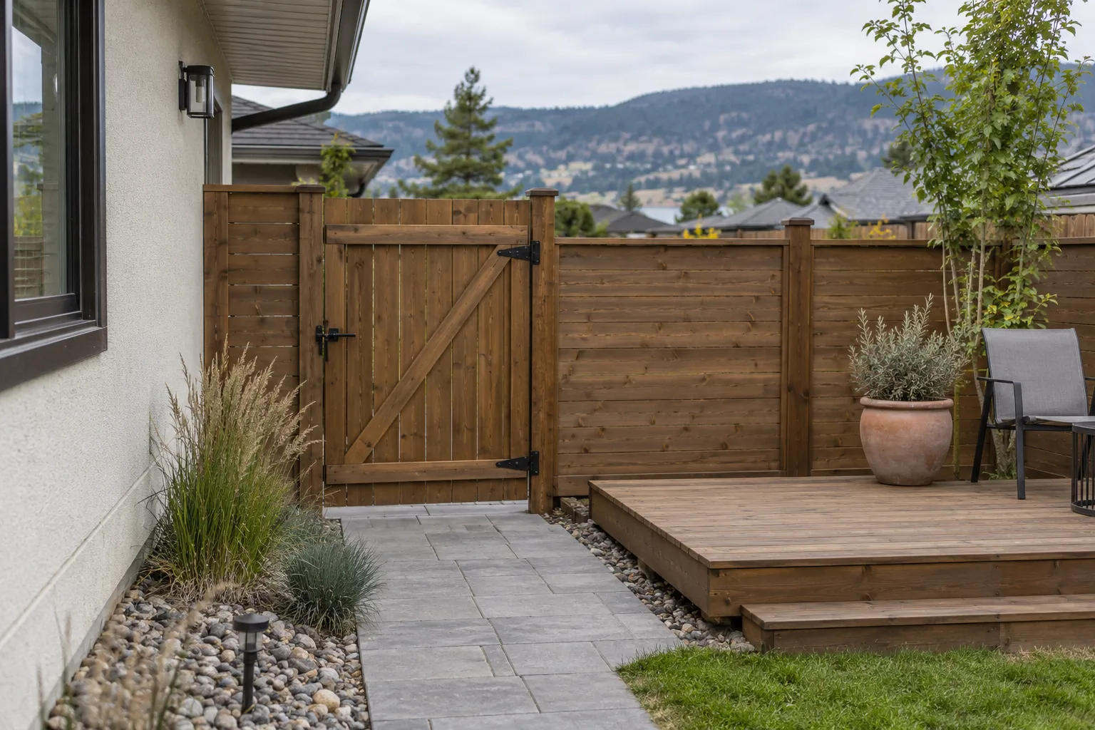Illustrative stained cedar fence and gate beside a low deck.