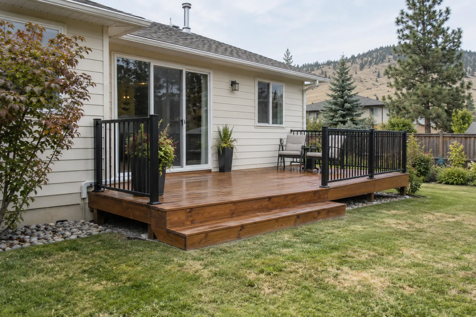 Illustrative finished cedar deck with black railings beside a cream home.